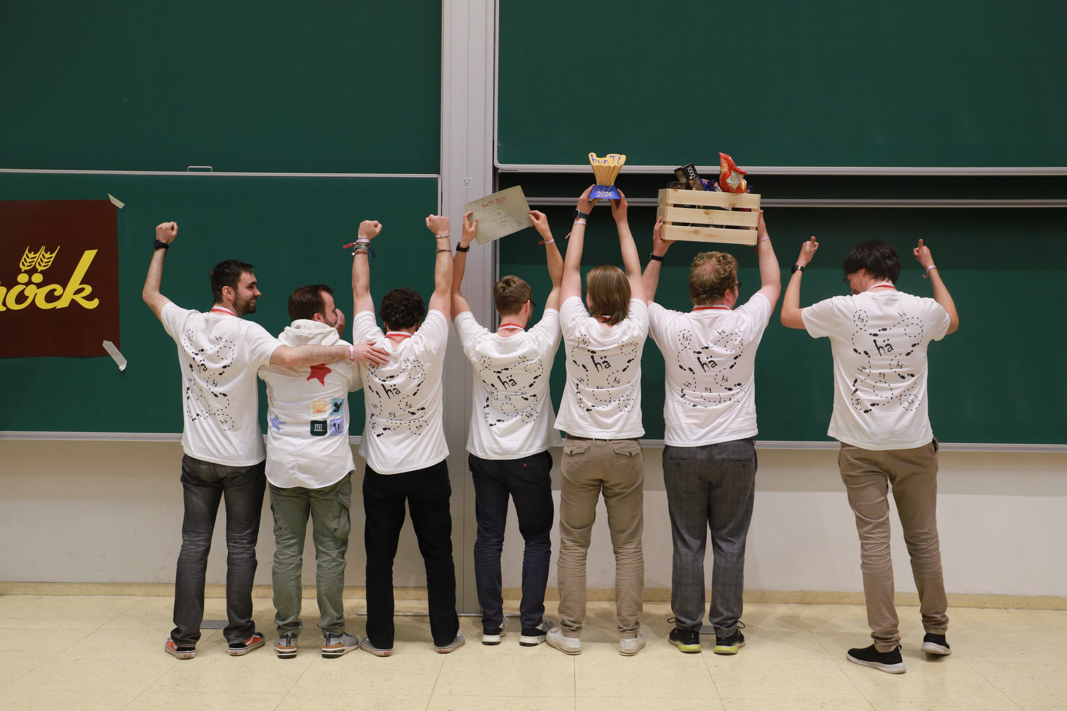 Team hä? mit Pokal, Urkunde und Geschenkkorb vor einer grünen Tafel